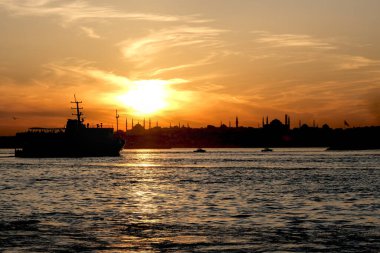 Sultanahmet ilçesinin silueti ve camileri renkli bir günbatımında. Boğaz 'da bir tekne hareket ediyor..