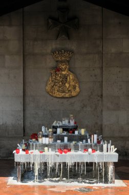 Altar adorned with candles. Wax dripped onto the floor.On the wall just above, the Virgin Mary keeps watch. clipart