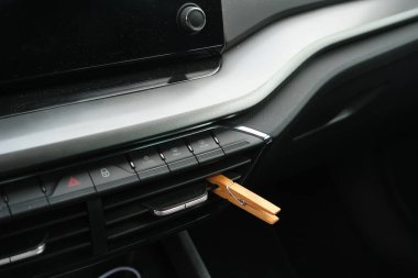 Installation of a clothespin on a car interior vent, impregnated with essential oil. To detoxify and remove unpleasant odours. clipart