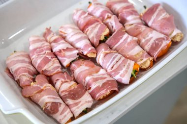 Peynir, sopasko ve bir dilim pastırmayla sarılmış jalapeno biberinden oluşan Jalapeno poppers adlı yemeğin hazırlığı. Ekmekler bir tabakta..