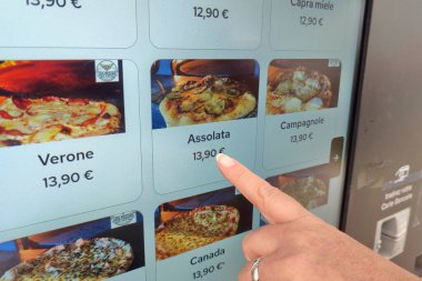 Pizza dağıtıcısının ekranından seçilen pizzayı gösteren bir kadın parmağı..