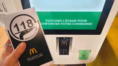 Petite Foret, Fransa - 08 31 2024: Bir McDonald 's restoranında büfenin yanında sipariş numarasını gösteren servis kartı tutan bir adamın eli.