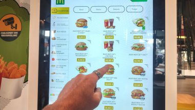 Petite Foret, Fransa - 08 31 2024: McDonald 's restoranındaki büfe ekranında bir hamburgeri işaret eden bir adam..