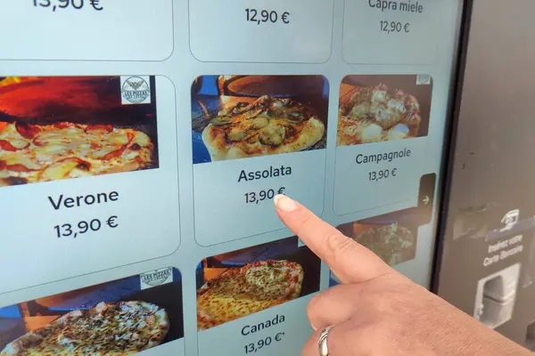 Pizza dağıtıcısının ekranından seçilen pizzayı gösteren bir kadın parmağı..