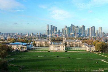 Londra, Birleşik Krallık - 11: 2024 Greenwich Park ve Eski Kraliyet Koleji 'nin geniş açılı manzarası, ağaçlarla çevrili, güneşli bir günde Canary Wharf' ın gökdelenleri.