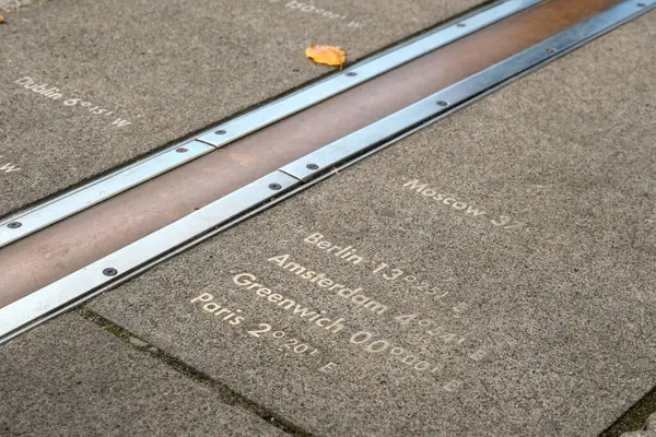 Greenwich, Londra 'da, küresel zaman dilimlerini temsil eden yere oyulmuş boylam işaretleriyle Birincil Meridyen' i gösteren çapraz kompozisyon.