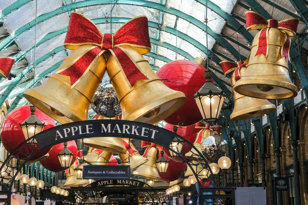 Londra, Birleşik Krallık - 11 Eylül 2024: Covent Garden, Londra 'da Noel temalı Apple Market, altın çanlar, kırmızı yaylar ve neşeli pazar tezgahları da dahil olmak üzere şenlikli süslemelerle süslendi.