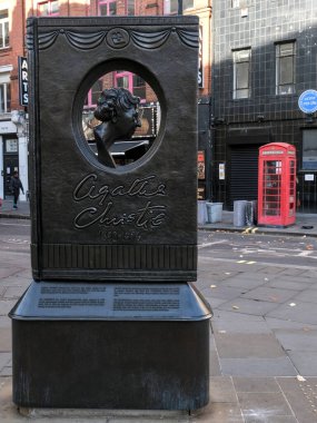 Londra, Birleşik Krallık - 11 11: 2024: Agatha Christie 'nin Londra' daki anıt heykeli, bronz bir kitap tasarımı içeriyor. Kırmızı telefon kulübesi ve şehir arkaplanı içeriği ekle.
