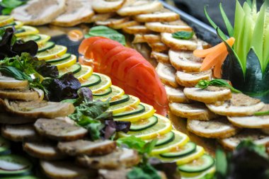 Zarif bir sunum için oyulmuş sebzelerle süslenmiş güzel bir tabak doldurulmuş tavuk dilimi, kabak, limon, domates ve taze yeşillik..