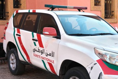 Marakeş, Fas - 12 31 2025: Geleneksel bir binanın yakınına park edilmiş kırmızı, yeşil ve beyaz işaretli bir Fas Ulusal Güvenlik aracı. Görünür çizikler ve arabada kir var..