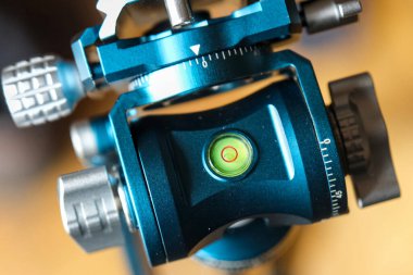 A close-up of a blue and silver tripod head with a bubble level, used for precise camera positioning. Intricate details and precision engineering. clipart