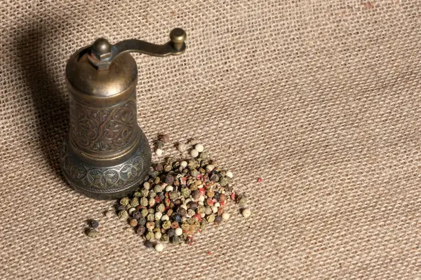 Eski bir pirinç öğütücü çuval bezi üzerine oturur ve yanında renkli biber karışımı bulunur. Kırsal, sıcak ve aromatik ortam.