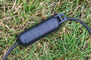 İki bölmesi olan siyah bir su geçirmez soket koruyucusu. Kabarık yüzeyleri ve güvenli ve çok yönlü elektrik koruması için dayanıklı tasarımı var..