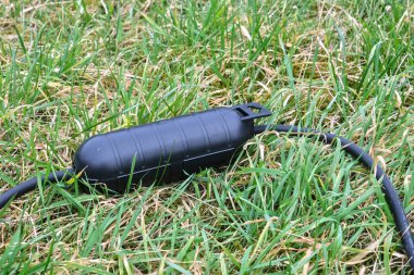 İki bölmesi olan siyah bir su geçirmez soket koruyucusu. Kabarık yüzeyleri ve güvenli ve çok yönlü elektrik koruması için dayanıklı tasarımı var..