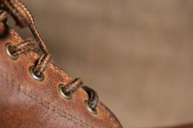 Görünür kırışıklıkları, püreleri ve sağlam dikişleri olan aşınmış kahverengi deri bir botun yakın çekimi. Kırsal arka plan engebeli, klasik estetiği güçlendirir..