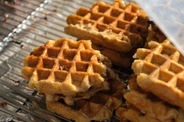 Soğutma rafında şerbet serpiştirilmiş altın, çıtır waffle 'lar, sıcak, tatlı aromalarını ve lezzetli dokularını yakalıyor, tadını çıkarmaya hazır..