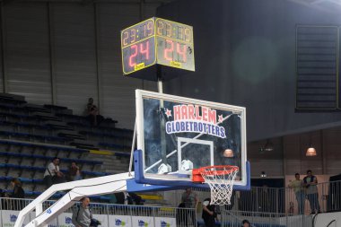 Orchies, Fransa - 03 28 2025: Harlem Globetrotters basketbol potası içinde canlı bir logo, saati ve skoru okuyan bir skor tahtası ve basketbol topu tutan coşkulu bir kalabalık.