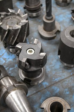 Endüstriyel hassasiyet ve mühendisliği gösteren, mavi bir yüzeyde sergilenen, musluklar ve kesiciler de dahil olmak üzere bir dizi metal makine aleti..