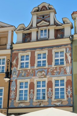 Poznan, Polonya - 04 21 2025: Pozna 'daki renkli Rönesans tarzı konak, parlak mavi gökyüzü altında canlı freskler ve sembolik figürlerle süslenmiş.