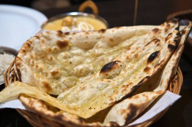 Bir sepetin içinde taze pişmiş sarımsak, Hint restoranı ortamında pirinç ve köri ile servis edilir, geleneksel Hint mutfağı sergilenir..