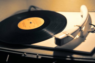 Eski bir plağın yakın plan çekimi sıcak bir nostaljik ambiyansı olan eski bir döner platformda dönüyor..