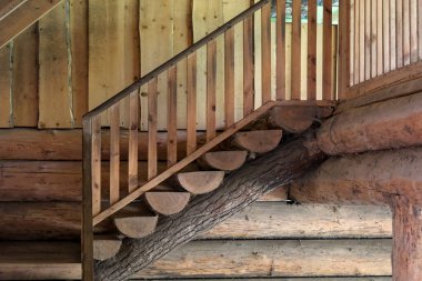 Odunluktaki ahşap bir merdivenin iç manzarası, el yapımı kütükler, doğal dokular ve geleneksel işçiliğin yer aldığı..