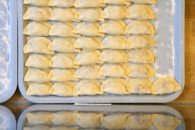 Taze ev yapımı, çeşitli şekillerde pierogi, kırsal bir mutfakta, tepsilerin üzerinde, sanatsal bir şekilde hazırlanmış ve dondurulmaya hazır..