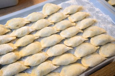 Taze ev yapımı, çeşitli şekillerde pierogi, kırsal bir mutfakta, tepsilerin üzerinde, sanatsal bir şekilde hazırlanmış ve dondurulmaya hazır..