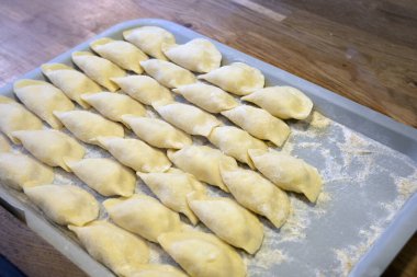 Taze ev yapımı, çeşitli şekillerde pierogi, kırsal bir mutfakta, tepsilerin üzerinde, sanatsal bir şekilde hazırlanmış ve dondurulmaya hazır..