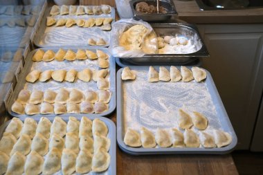 Taze ev yapımı, çeşitli şekillerde pierogi, kırsal bir mutfakta, tepsilerin üzerinde, sanatsal bir şekilde hazırlanmış ve dondurulmaya hazır..