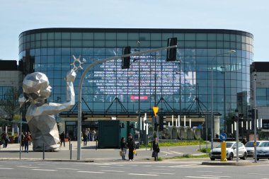 Poznan, Polonya - 04 25 2025: Polonya 'nın Poznan kentindeki modern heykel ve cam kaplı Posnania alışveriş merkezi, yayalar ve ön planda trafik.