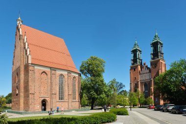 Poznan, Polonya - 04 26 2025: St. Peter ve Paul 'un tarihi ikiz Bazilikası, Polonya' nın Poznan kentindeki açık mavi bir gökyüzünün altında, Ostrow Tumski 'de yeşillikler içinde yükseliyor.