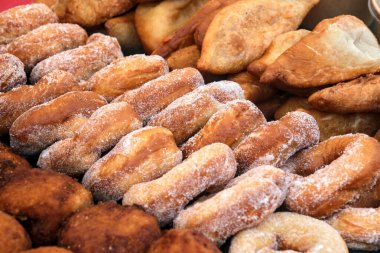 Çeşitli kızarmış hamur işleri ve şeker kaplı çörekler bir market tezgahına istiflenmiş altın dokular ve lezzetli ev yapımı ikramlar sergileniyor..