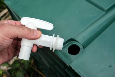 Bir delik testeresi kullanarak yağmur varili musluğu kurmak. Musluğu su toplama kabına monte etmeden önce doğru matkap boyutu seçiliyor.