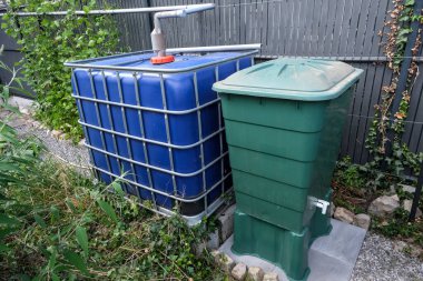 İki su tankını birbirine bağlayan yağmur suyu taşma sistemi. Yeşil tank, sürdürülebilir bahçe kullanımı için mavi kaptaki fazlalıkları topluyor.