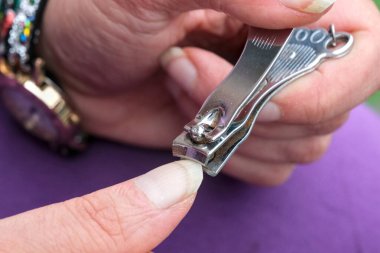 Tırnağını kesmek için metal tırnak makası kullanan, elleri ve tırnaklarını detaylıca gösteren birinin yakın çekimi..