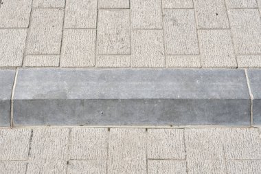 Doğal taş kaldırımlı mavi bir kaldırıma yakın çekim, şehir dokusunu, geometriyi ve açık hava ışıklarındaki nötr tonları gösterir..