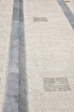 Doğal taş kaldırımlı mavi bir kaldırıma yakın çekim, şehir dokusunu, geometriyi ve açık hava ışıklarındaki nötr tonları gösterir..