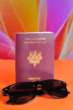Fransız pasaportu ve parlak arkaplanda siyah güneş gözlüğü seyahat, tatil ve macerayı simgeliyor..
