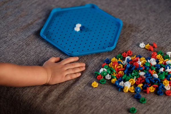 Toys for fine motor skill development. Toddler playing peg board mosaic toy at home, inserting colorful pins, Creative and educational games for small children. Child development and sensory activity