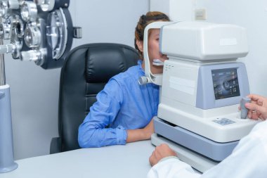 Yakışıklı erkek göz doktoru modern bir klinikte çekici bir genç kadının vizyonunu inceliyor, göz doktorları ve hastalar.