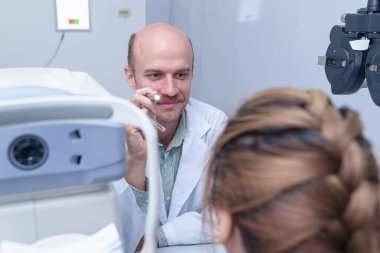 Doktor göz doktoru hastanın gözlerini muayene eder..