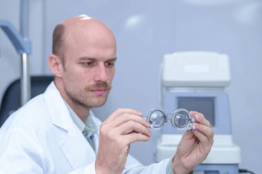 Optometristin göz hekimliği kliniğinde bir messbrille tutarken görüntüsü.