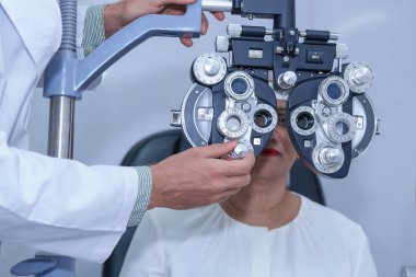 Çekici erkek göz doktoru, modern klinikte, doktorlarda ve göz hekimliği kliniğinde orta yaşlı bir kadının görme duyusunu kontrol ediyor..