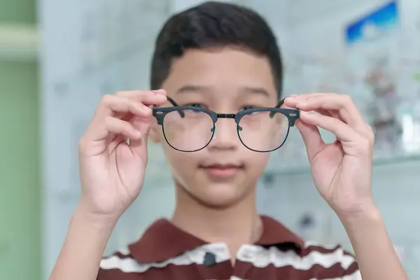 Boy choosing eyeglass frames in an eyeglass assembly shop