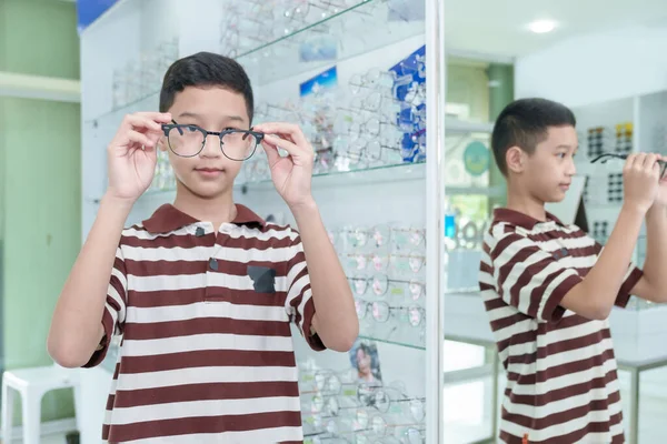 Boy choosing eyeglass frames in an eyeglass assembly shop