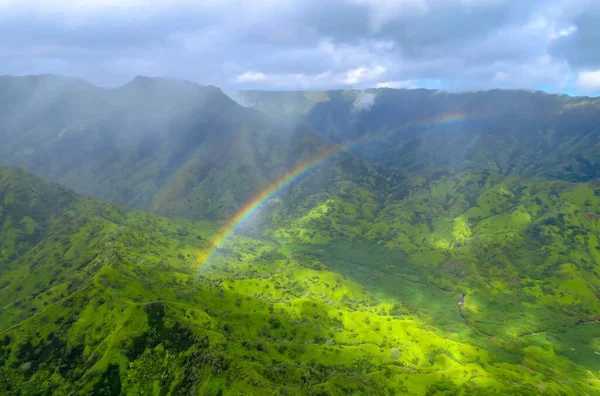 Rainbow over green valley and mountains, panorama shot from a helicopter at Na Pali Coast State Wilderness Park, Kauai, Hawaii, USA