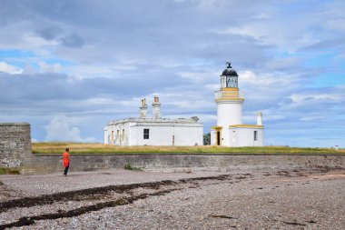 Black Island, İskoçya, İngiltere ve Avrupa 'daki Chanonry Point' teki beyaz deniz fenerine yürüyen kişi.