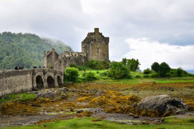 Dornie, İngiltere - 7 Temmuz 2023: Popüler Eilean Donan Şatosu 'na köprüden geçen turistler, İskoçya' nın ünlü simgesi, Avrupa seyahati