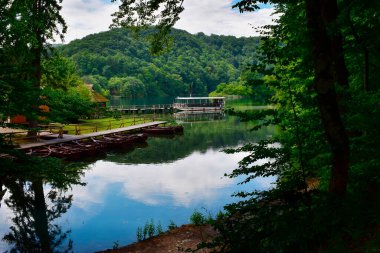 Feribot rıhtıma yanaştı ve kürek çekenler rıhtımda demirledi, yemyeşil bir çevrede. Plitvice Gölleri Ulusal Parkı, güzel Hırvatistan, Balkanlar 'ı keşfetmek, Avrupa' yı gezmek.